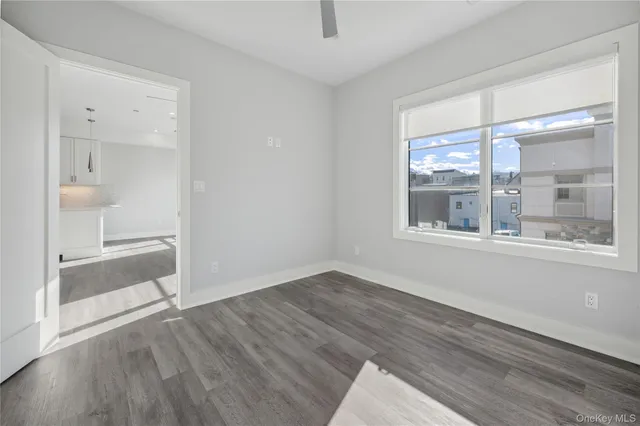 a view of an empty room with a window and wooden floor