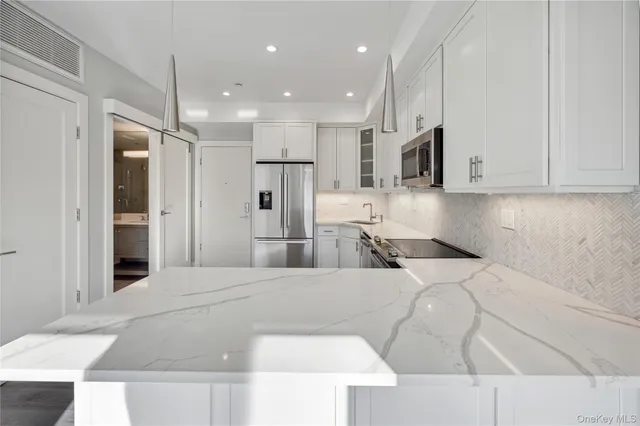 a large white kitchen with kitchen island and stainless steel appliances