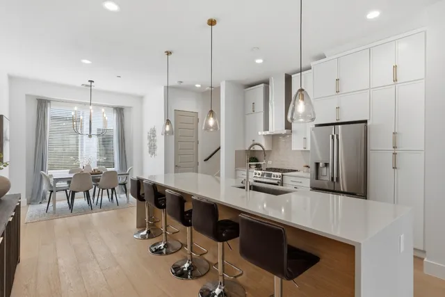 a kitchen with stainless steel appliances granite countertop a table chairs stove and refrigerator