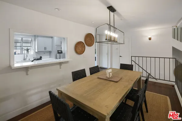 a dining room with wooden floor a chandelier a wooden table and chairs