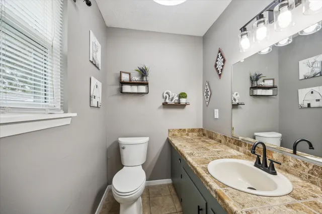 a bathroom with a granite countertop toilet a sink and a mirror