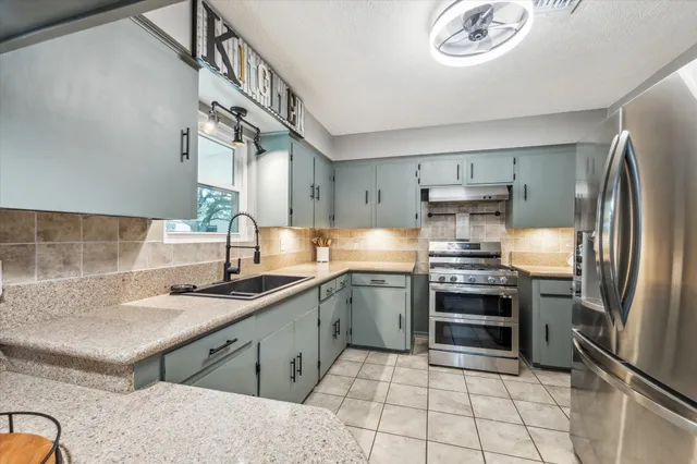 a kitchen with stainless steel appliances granite countertop a sink stove and refrigerator
