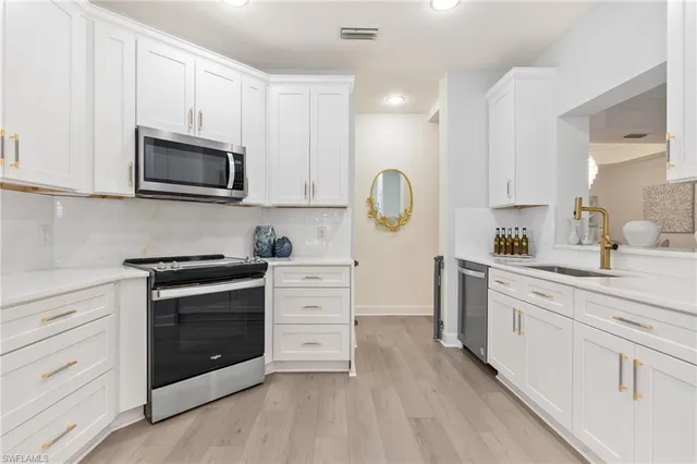 a kitchen with granite countertop white cabinets stainless steel appliances and sink