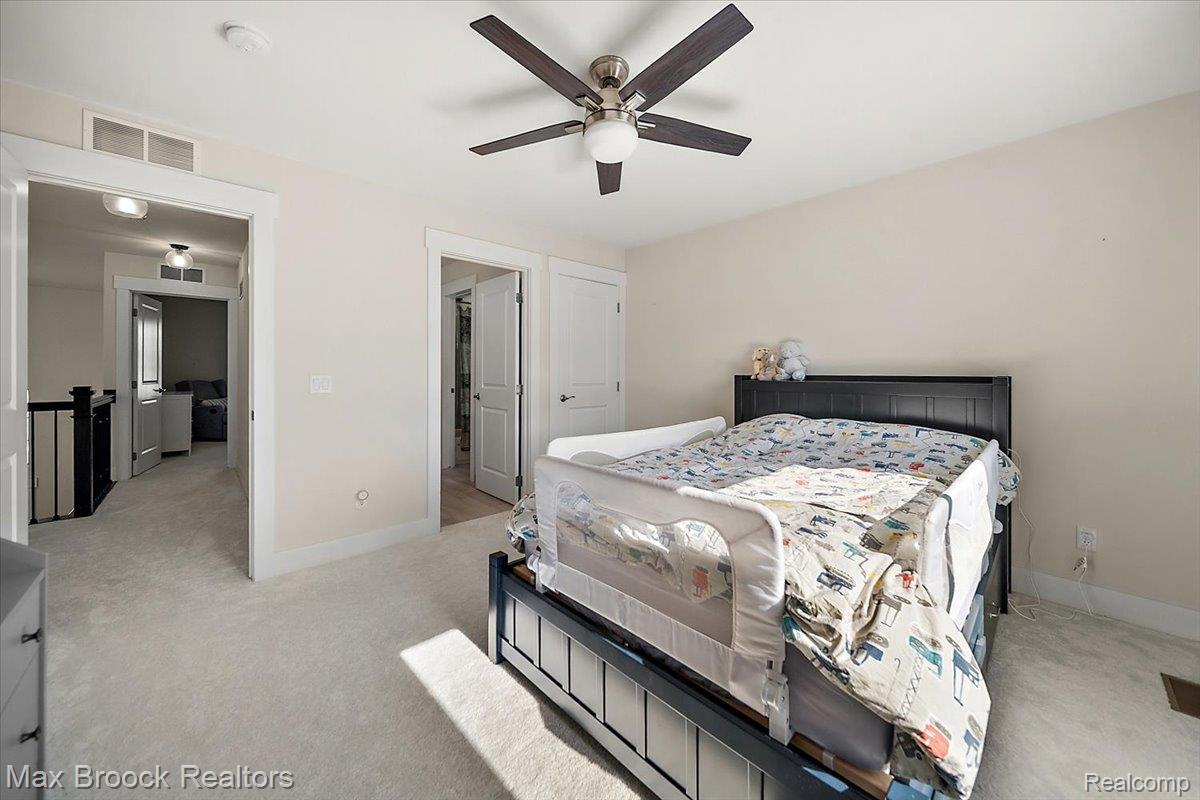 1942 Nottingham Drive Rochester, MI 48307 - Photo 56 of 97 Carpeted room with a ceiling fan light fixture, leading to an open hallway with a black handrail and white balusters