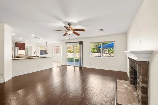 a view of an empty room with window and wooden floor