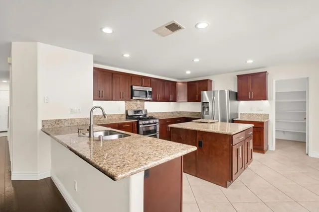 a kitchen with stainless steel appliances granite countertop a sink a stove and a refrigerator