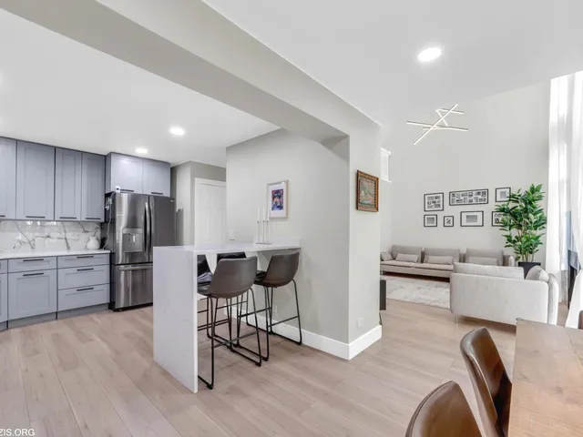 a kitchen with stainless steel appliances kitchen island granite countertop a refrigerator a stove a sink a dining table and chairs with wooden floor