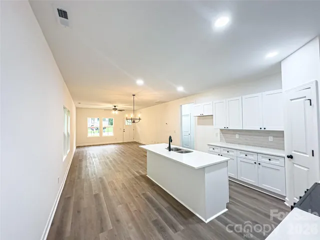 a open kitchen with kitchen island white cabinets and white appliances