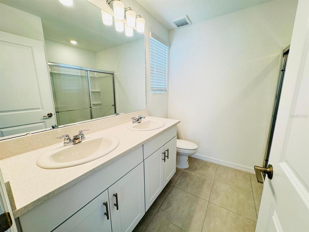 3140 Skyline Loop Kissimmee, FL 34758 - Photo 18 of 27 a bathroom with a sink a toilet and a mirror
