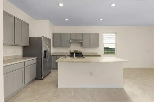 a kitchen with stainless steel appliances granite countertop a refrigerator a stove a sink and a microwave