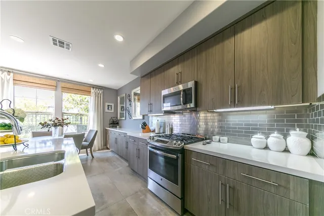 a kitchen with stainless steel appliances a stove a sink a microwave a dining table and chairs