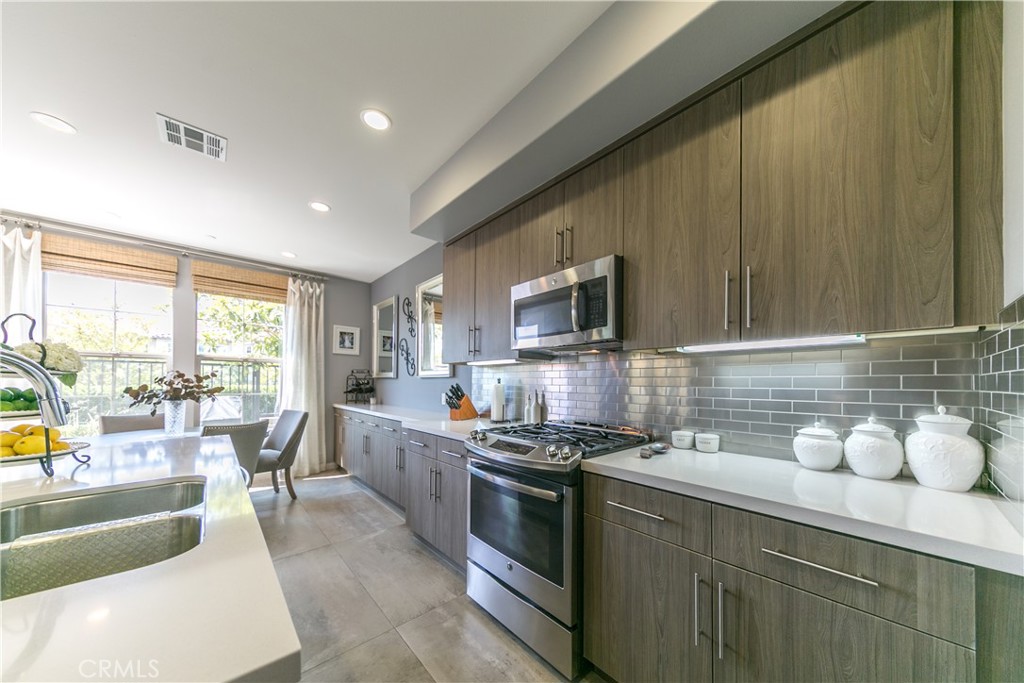 308 Finch Lake Forest, CA 92630 - Photo 8 of 35 a kitchen with stainless steel appliances a stove a sink a microwave a dining table and chairs