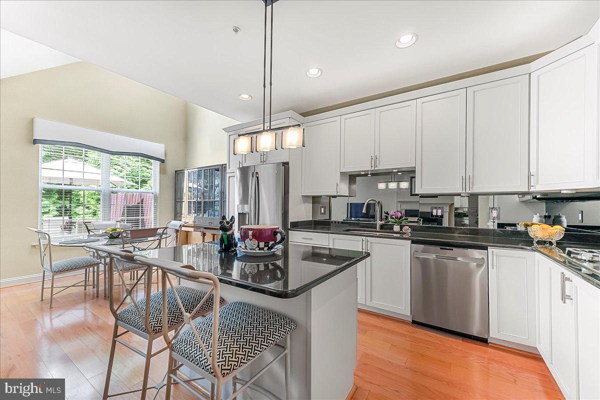 1132 Brian's Way Wayne, PA 19087 - Photo 12 of 45 a kitchen with stainless steel appliances granite countertop a stove a sink a microwave a dining table and chairs with wooden floor