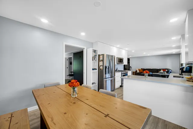 a living room with stainless steel appliances kitchen island a table and chairs in it