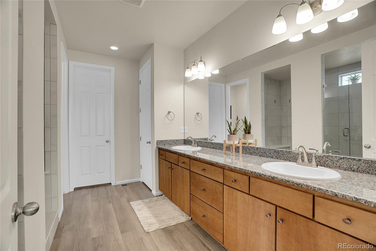 815 Bear Peak Road Erie, CO 80516 - Photo 18 of 32 a spacious bathroom with a granite countertop double vanity sink a mirror and a shower
