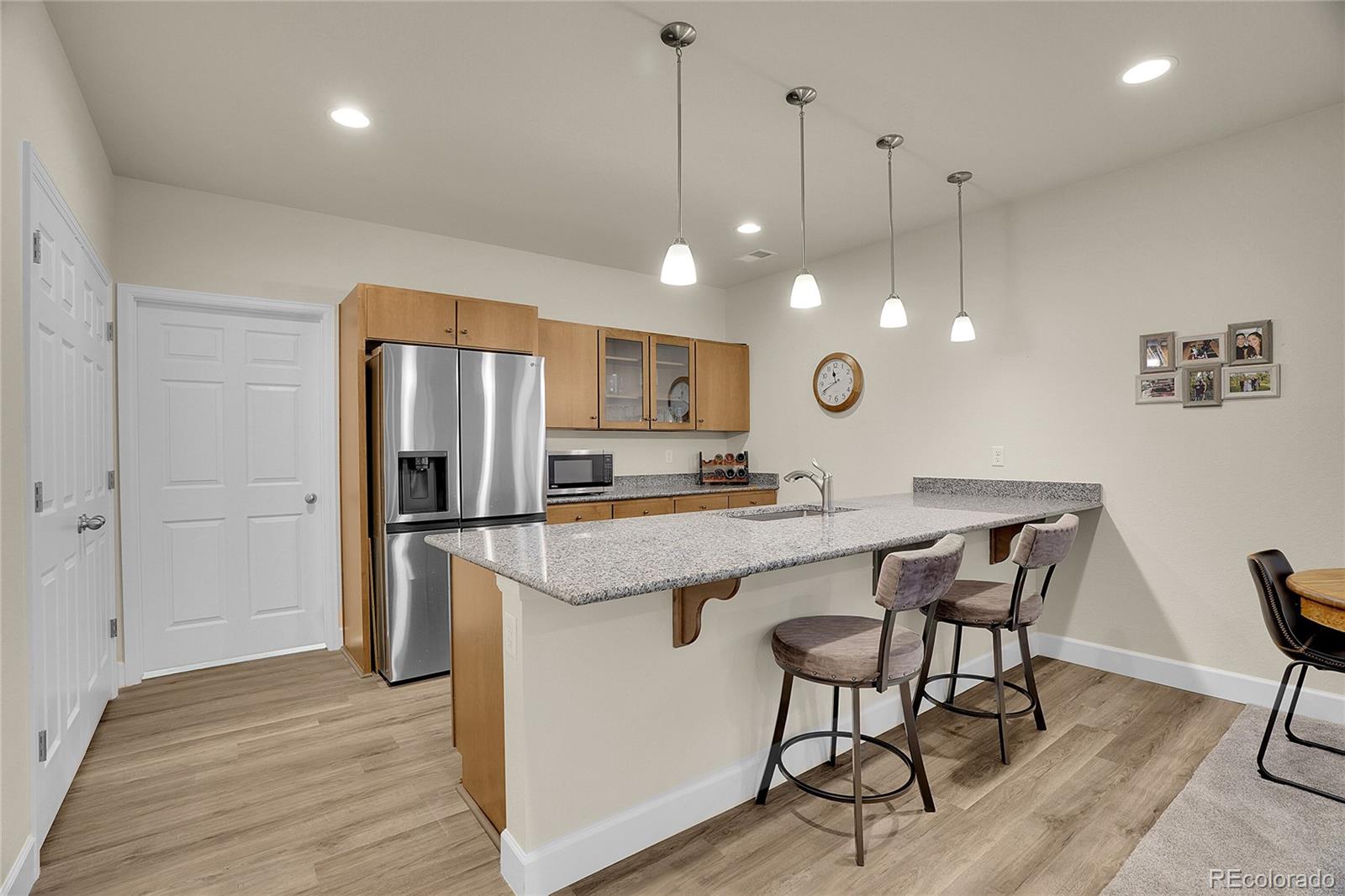 815 Bear Peak Road Erie, CO 80516 - Photo 23 of 32 a kitchen with stainless steel appliances granite countertop a refrigerator a sink dishwasher a dining table and chairs with wooden floor