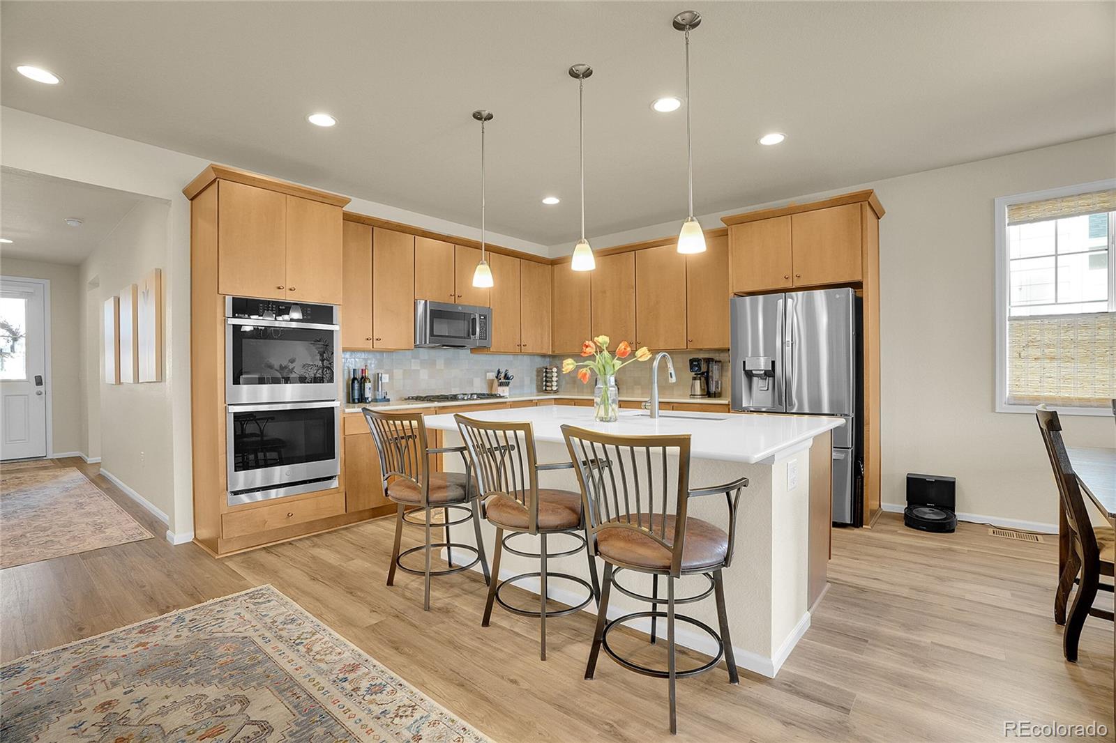 815 Bear Peak Road Erie, CO 80516 - Photo 7 of 32 a kitchen with stainless steel appliances a dining table chairs and refrigerator