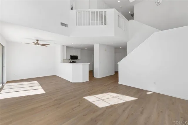 a view of a livingroom with wooden floor and kitchen space