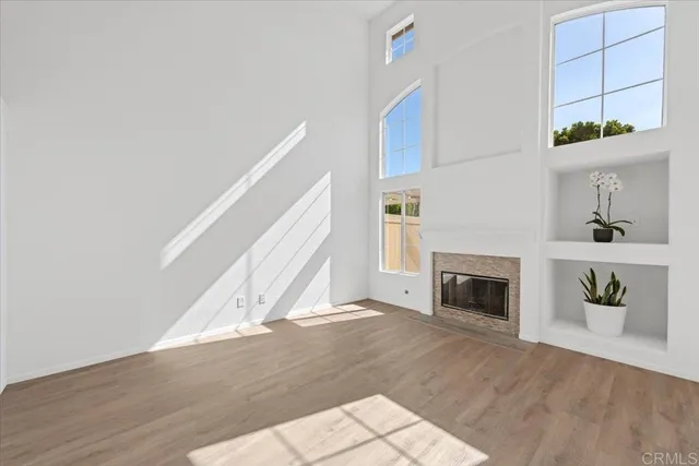 a view of an empty room with wooden floor fireplace and a window