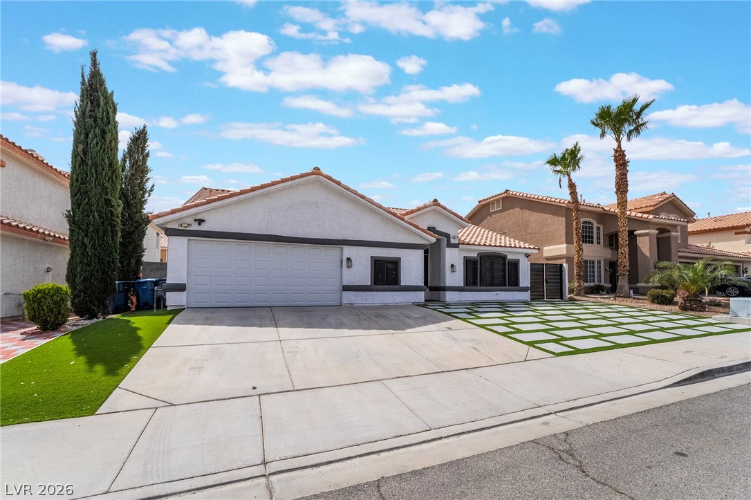 9171 West Viking Road Las Vegas, NV 89147 - Photo 3 of 43 A well-maintained facade with a two-car garage and distinctive tiled roofing under a wide blue sky.
