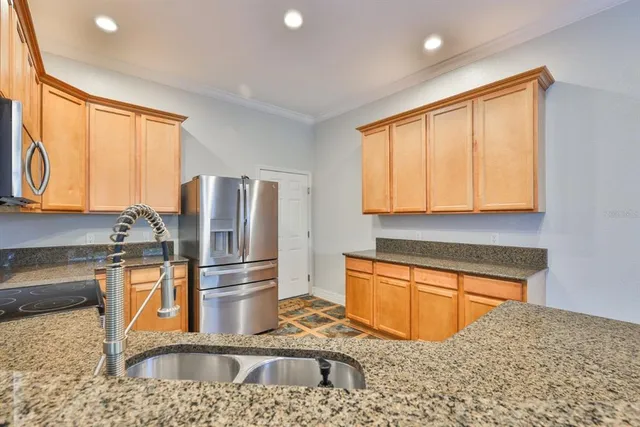 a kitchen with stainless steel appliances granite countertop a sink and a refrigerator