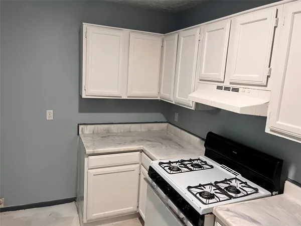 a kitchen with granite countertop a stove a sink and a microwave