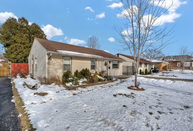 a front view of a house with a yard covered in snow