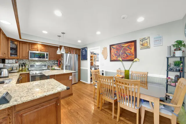 a kitchen with stainless steel appliances granite countertop sink stove refrigerator dining table and chairs