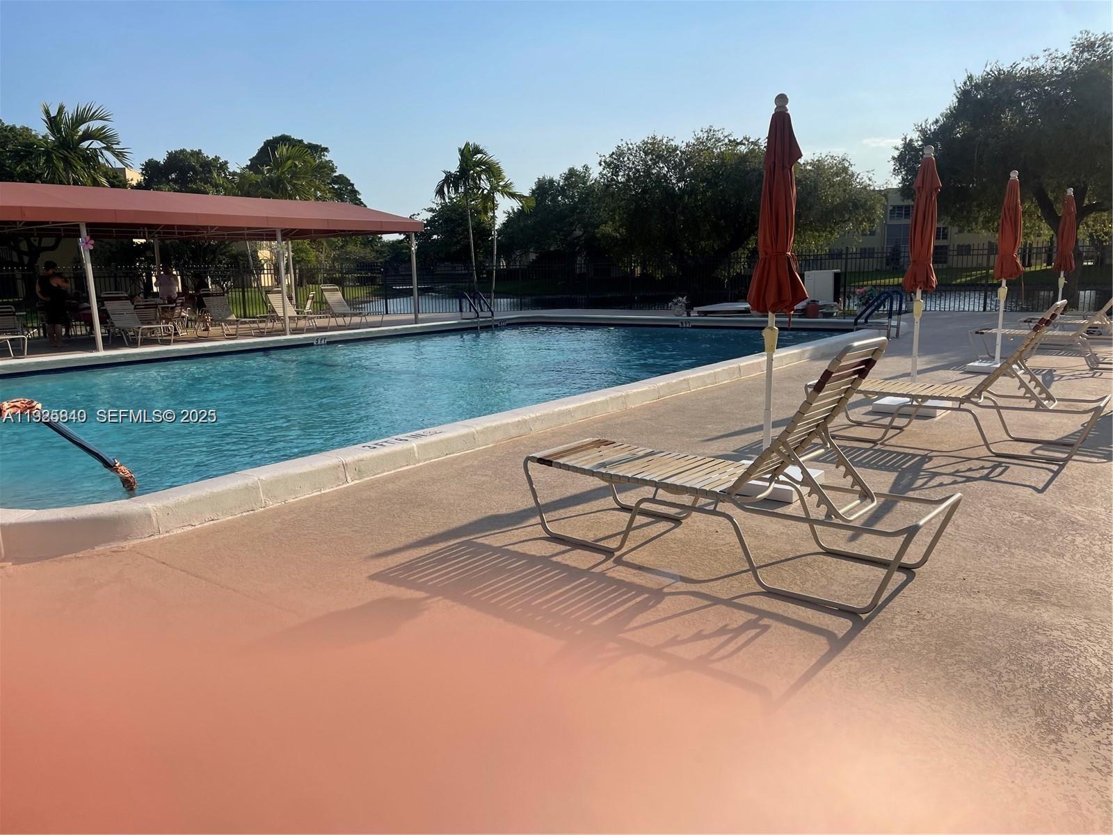 5961 Northwest 61st Avenue, Unit 208 Tamarac, FL 33319 - Photo 9 of 11 a view of a swimming pool with a patio and a yard