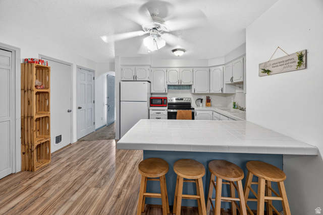 1218 East 100 South Logan, UT 84321 - Photo 6 of 23 Kitchen featuring white cabinetry, white appliances, a tile countertop, and wood-finish flooring