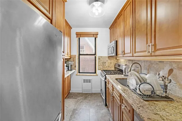 a kitchen with stainless steel appliances granite countertop a sink a stove a refrigerator and cabinets