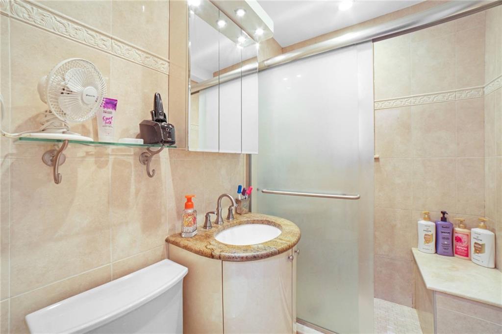 2310 Ocean Parkway, Unit 3J Brooklyn, NY 11223 - Photo 5 of 8 a bathroom with a sink a toilet and shower curtain