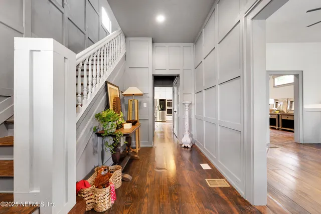 a hallway with wooden floor stairs and furniture