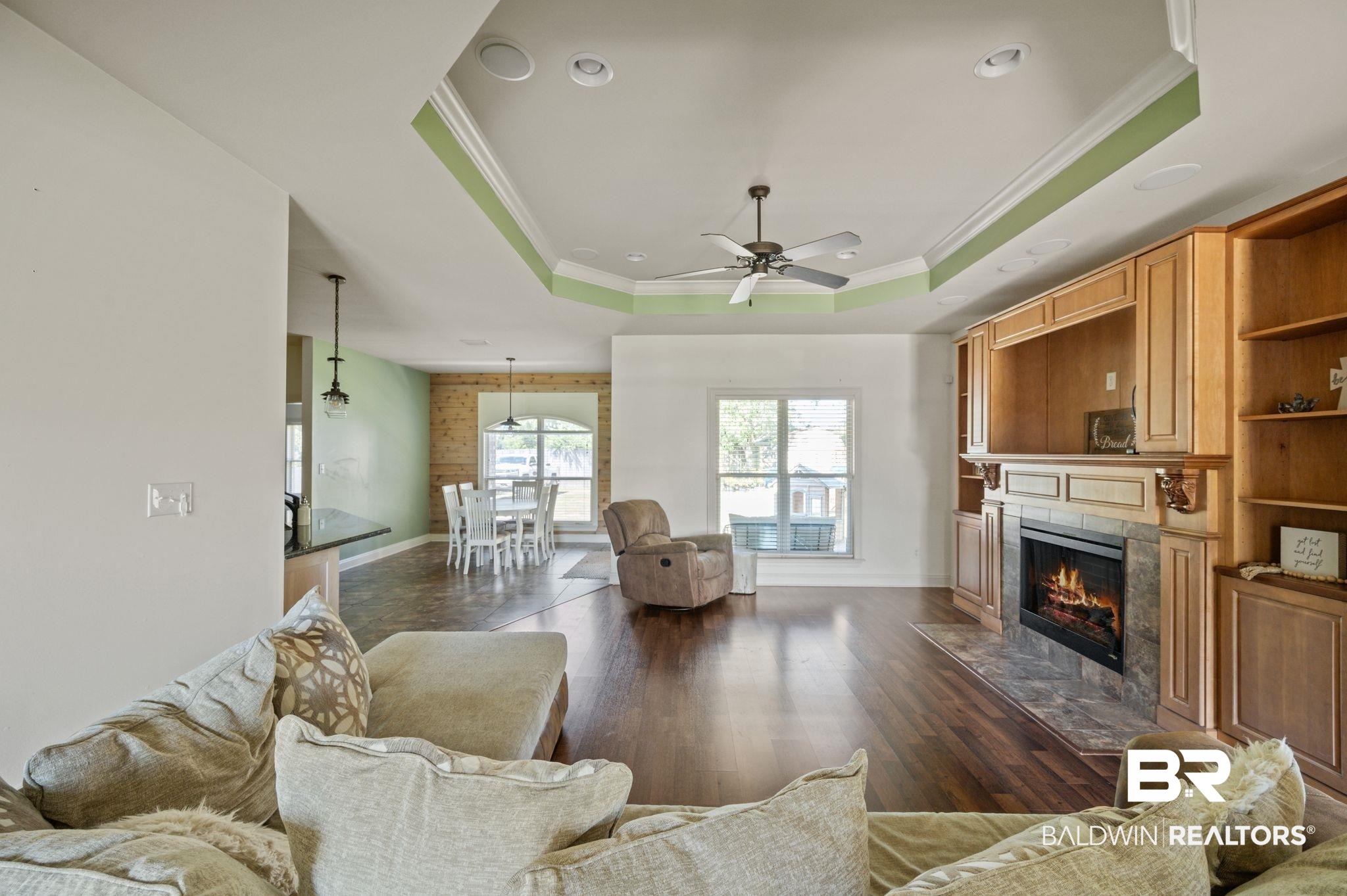 3879 Symphony Way West Semmes, AL 36575 - Photo 7 of 34 Living room featuring crown molding, a raised ceiling, a tiled fireplace, dark wood-type flooring, and ceiling fan