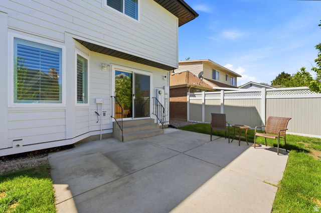 1405 Vintry Lane Murray, UT 84121 - Photo 34 of 44 Rear exterior featuring a concrete patio, sliding glass door, and a bay window