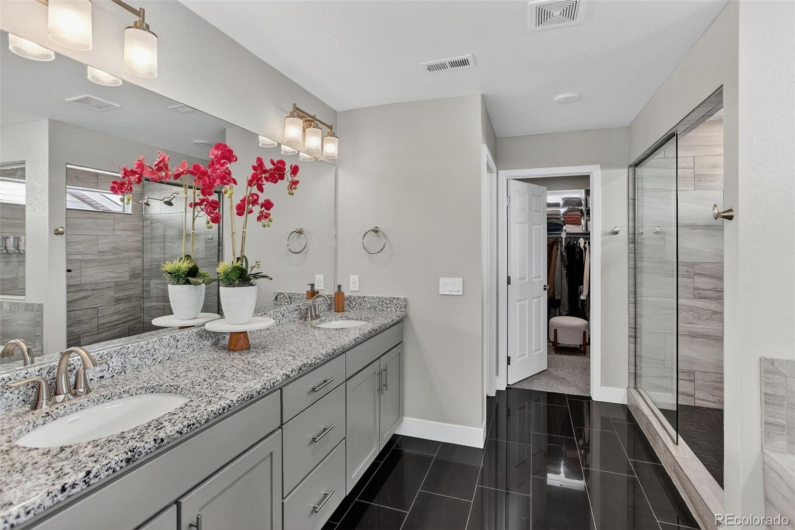 5012 Liverpool Street Denver, CO 80249 - Photo 23 of 49 a bathroom with a granite countertop sink a mirror and shower