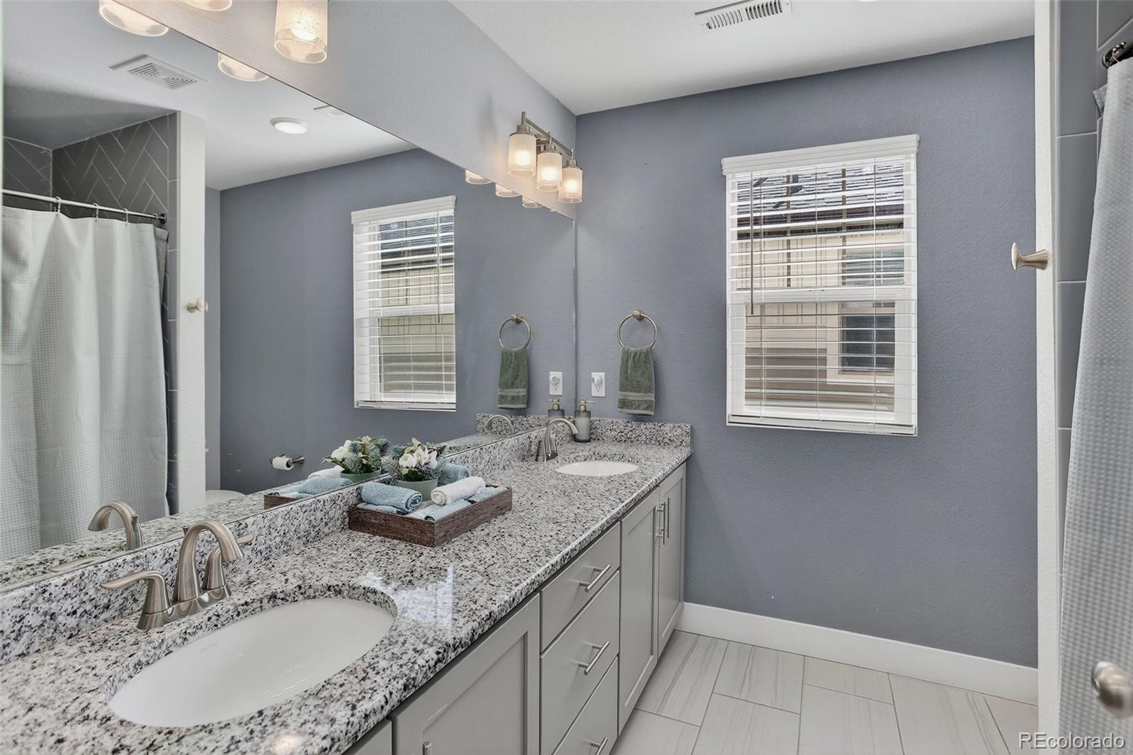 5012 Liverpool Street Denver, CO 80249 - Photo 30 of 49 a bathroom with a granite countertop sink a large mirror and a shower