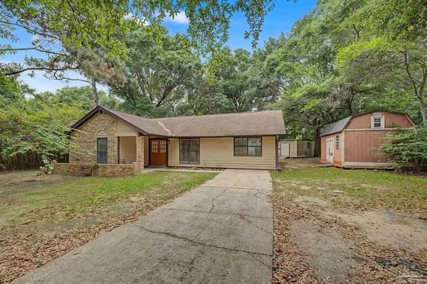 a front view of a house with a yard and large tree