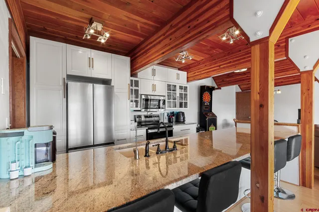 a kitchen with stainless steel appliances kitchen island granite countertop a table chairs and a refrigerator