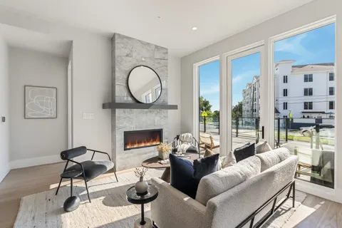 a living room with furniture a fireplace and a floor to ceiling window
