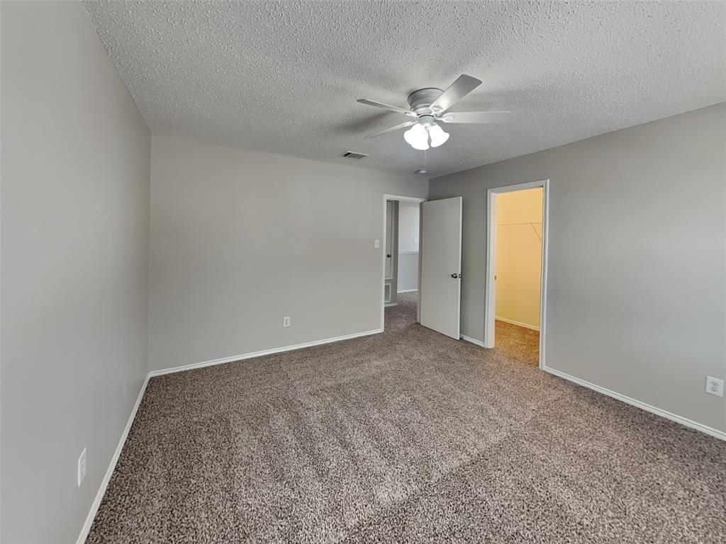 216 Turning Tree Road Wilmer, TX 75172 - Photo 12 of 20 Unfurnished bedroom with a walk in closet, carpet floors, a ceiling fan, and a textured ceiling