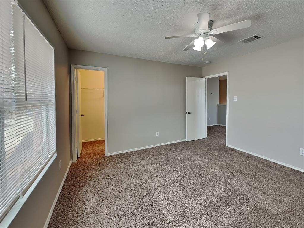 216 Turning Tree Road Wilmer, TX 75172 - Photo 13 of 20 Unfurnished bedroom with carpet floors, a spacious closet, a textured ceiling, and a ceiling fan