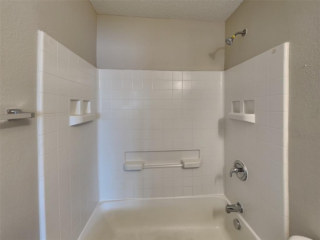 216 Turning Tree Road Wilmer, TX 75172 - Photo 15 of 20 Bathroom featuring a textured wall, bathing tub / shower combination, and a textured ceiling