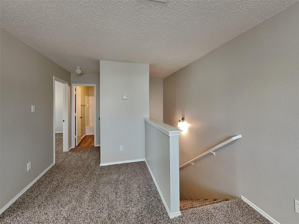 216 Turning Tree Road Wilmer, TX 75172 - Photo 17 of 20 Hallway featuring an upstairs landing, carpet floors, and a textured ceiling