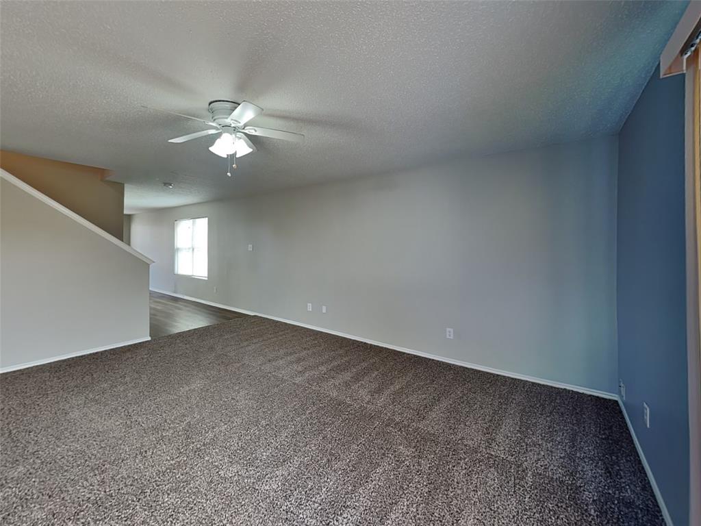 216 Turning Tree Road Wilmer, TX 75172 - Photo 3 of 20 Unfurnished room featuring dark carpet, a textured ceiling, and a ceiling fan