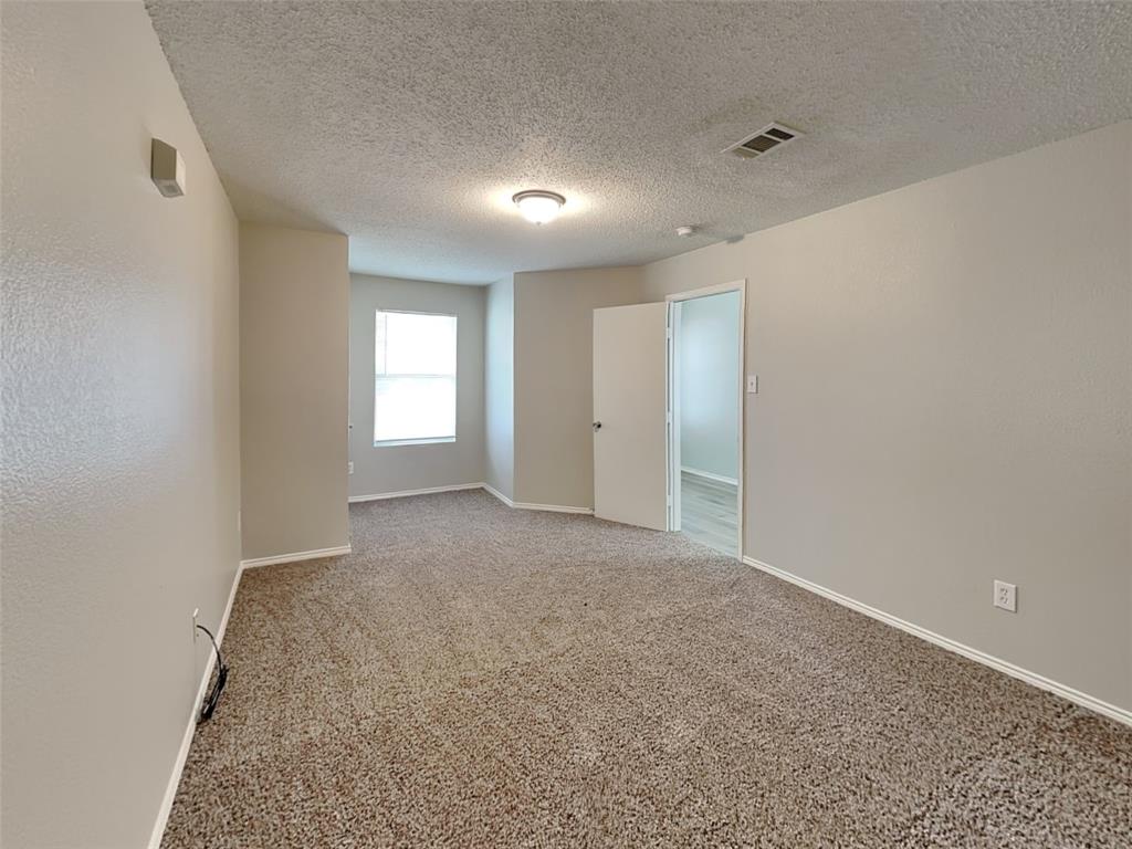 216 Turning Tree Road Wilmer, TX 75172 - Photo 4 of 20 Carpeted empty room featuring baseboards and a textured ceiling