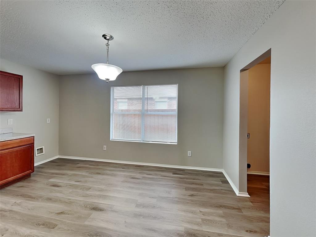 216 Turning Tree Road Wilmer, TX 75172 - Photo 5 of 20 Unfurnished dining area featuring light wood-style flooring and a textured ceiling