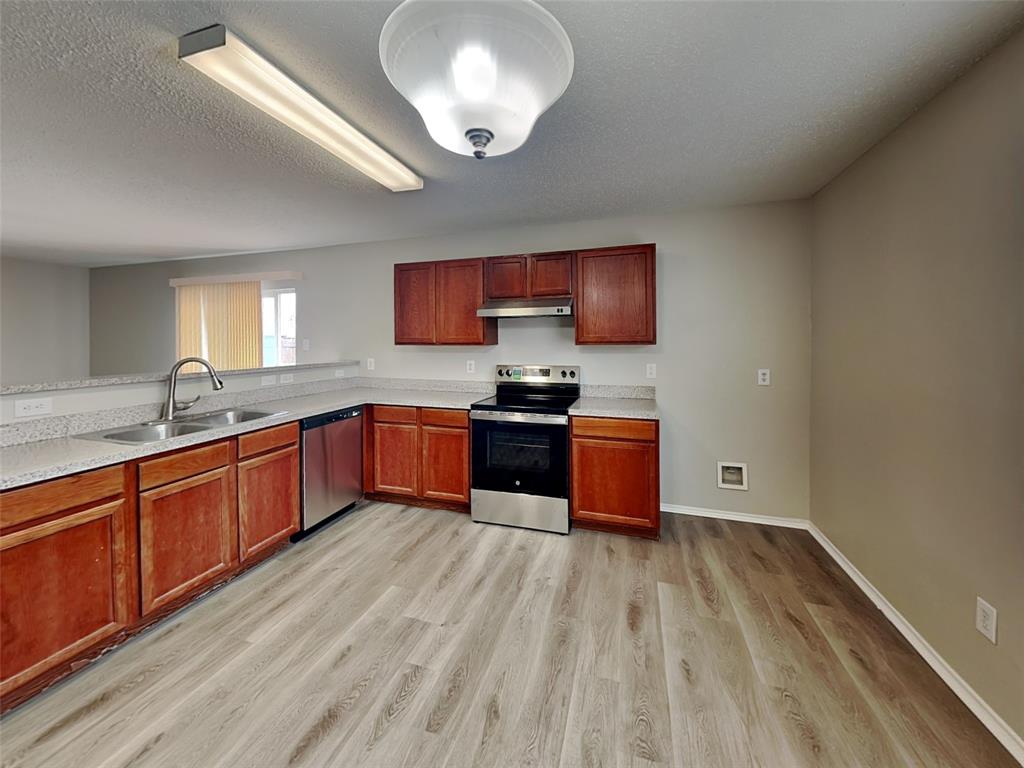 216 Turning Tree Road Wilmer, TX 75172 - Photo 6 of 20 Kitchen featuring stainless steel appliances, a textured ceiling, light wood-type flooring, and under cabinet range hood