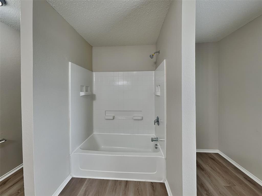 216 Turning Tree Road Wilmer, TX 75172 - Photo 10 of 20 Bathroom featuring shower / bath combination, light wood-style flooring, and a textured ceiling