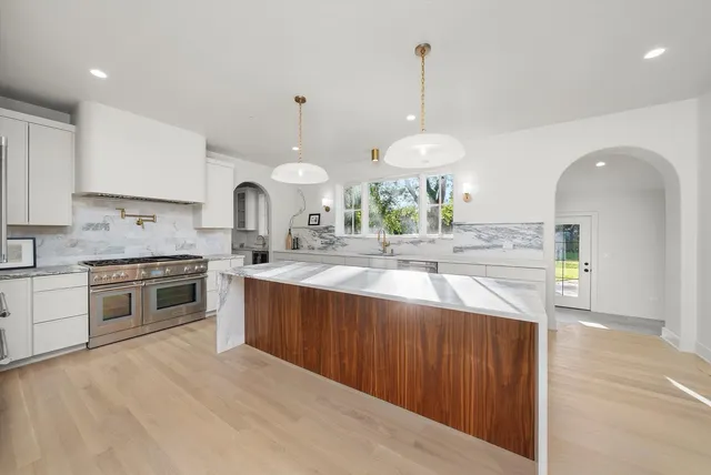 a large kitchen with stainless steel appliances granite countertop a lot of counter space and wooden floors
